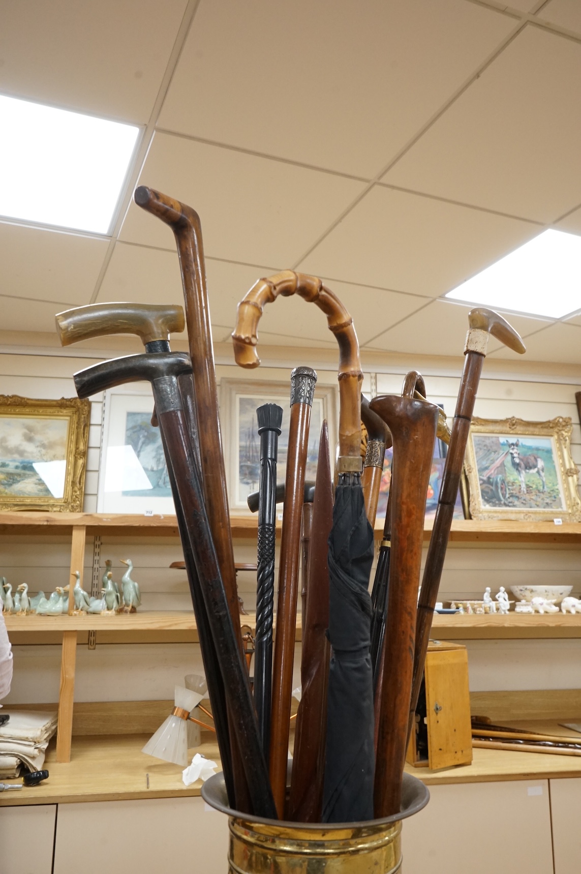 A collection of various walking sticks, some silver mounted, an umbrella with bamboo handle and a brass stick stand, stick stand 45cm high